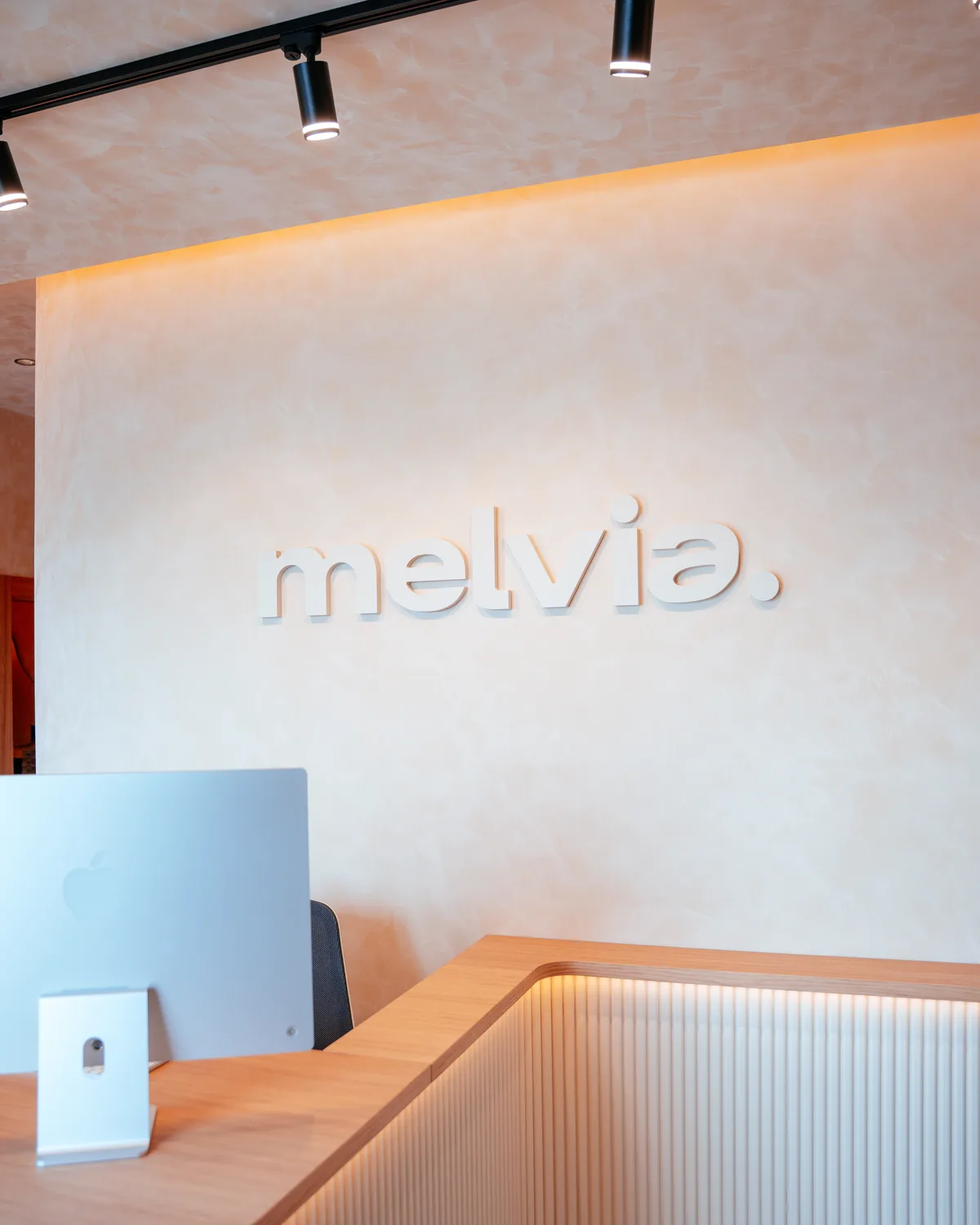 Pared de la recepción de Melvia con el logotipo en relieve