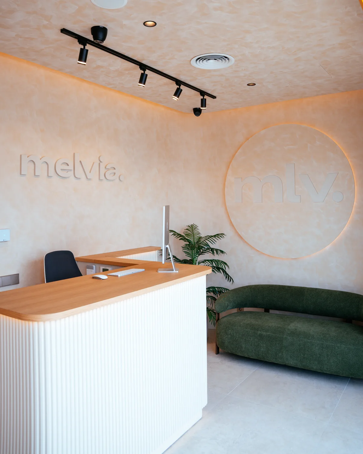 Recepción de Melvia con el sofá verde y el logotipo mlv. retroiluminado