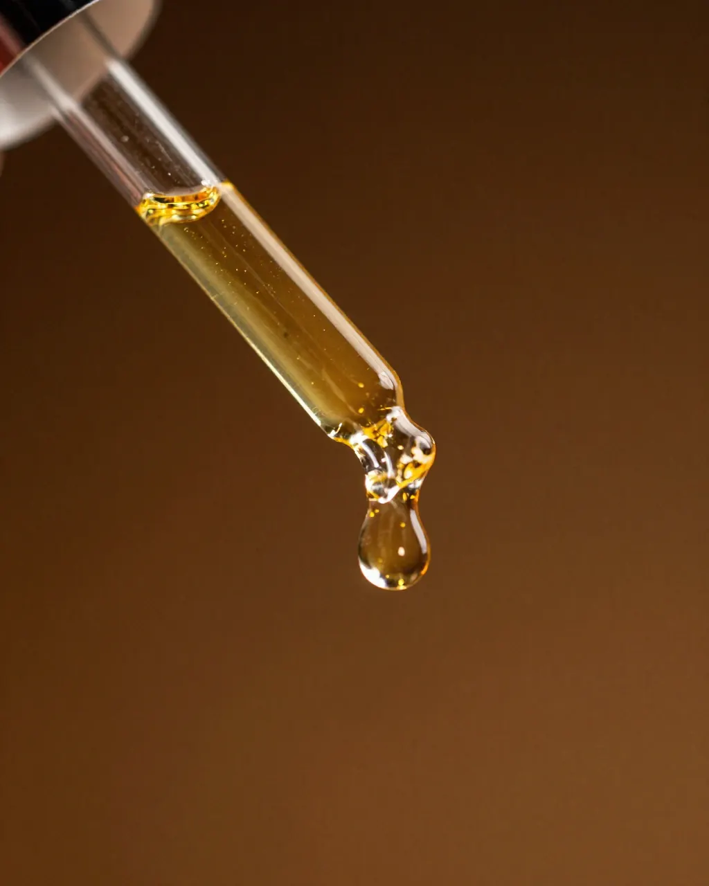 Gota de sérum dorado cayendo de un cuentagotas